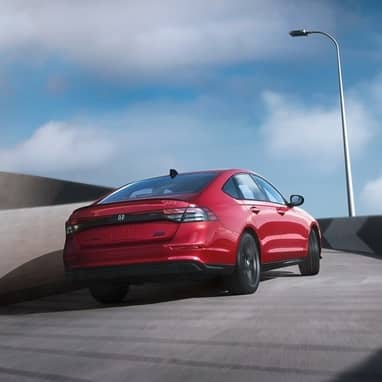 2026 Honda Accord, 3/4 rear passenger view, driving up the circular ramp of the parking structure during the day.